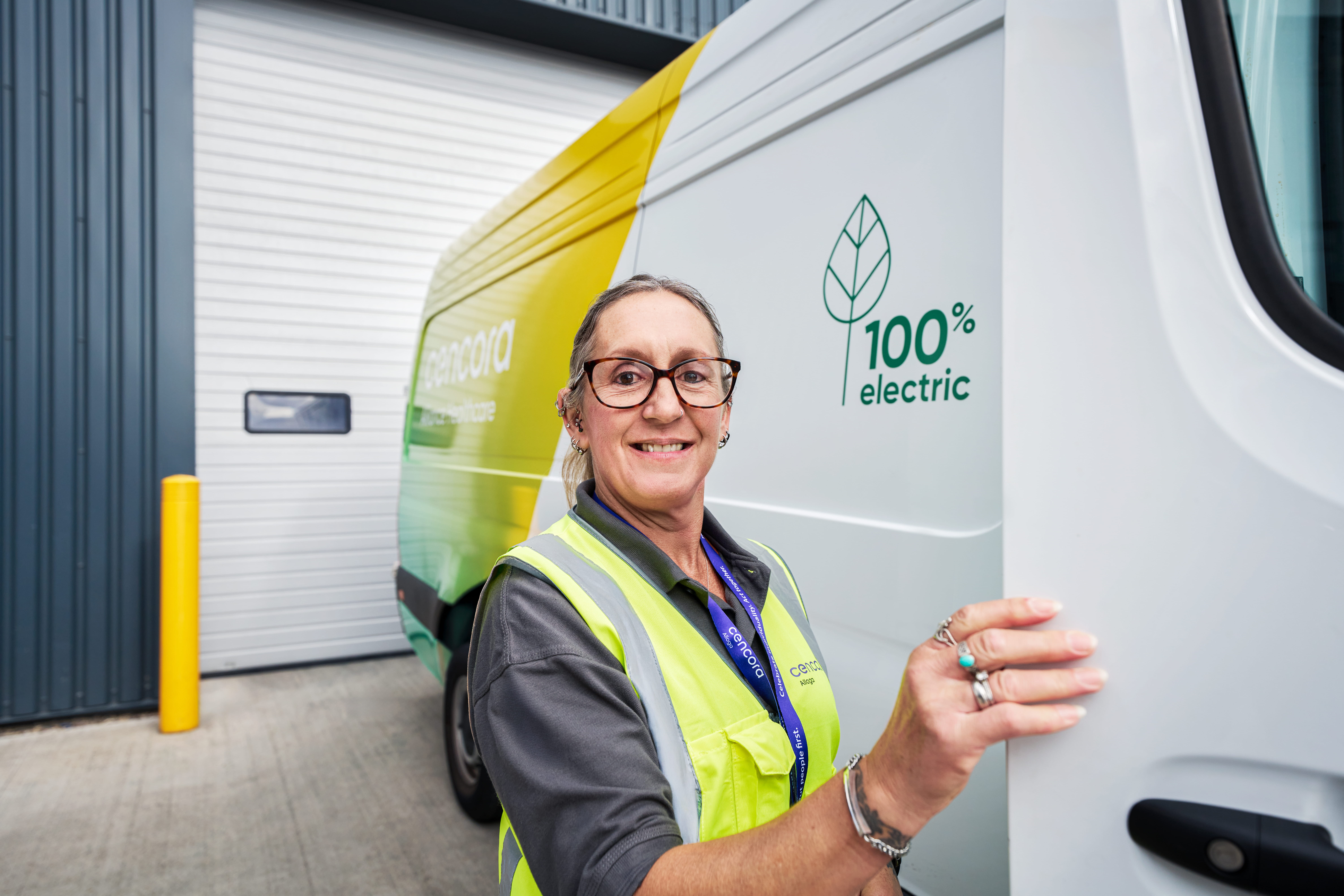 Smiling female employee opening the door of a delivery van.