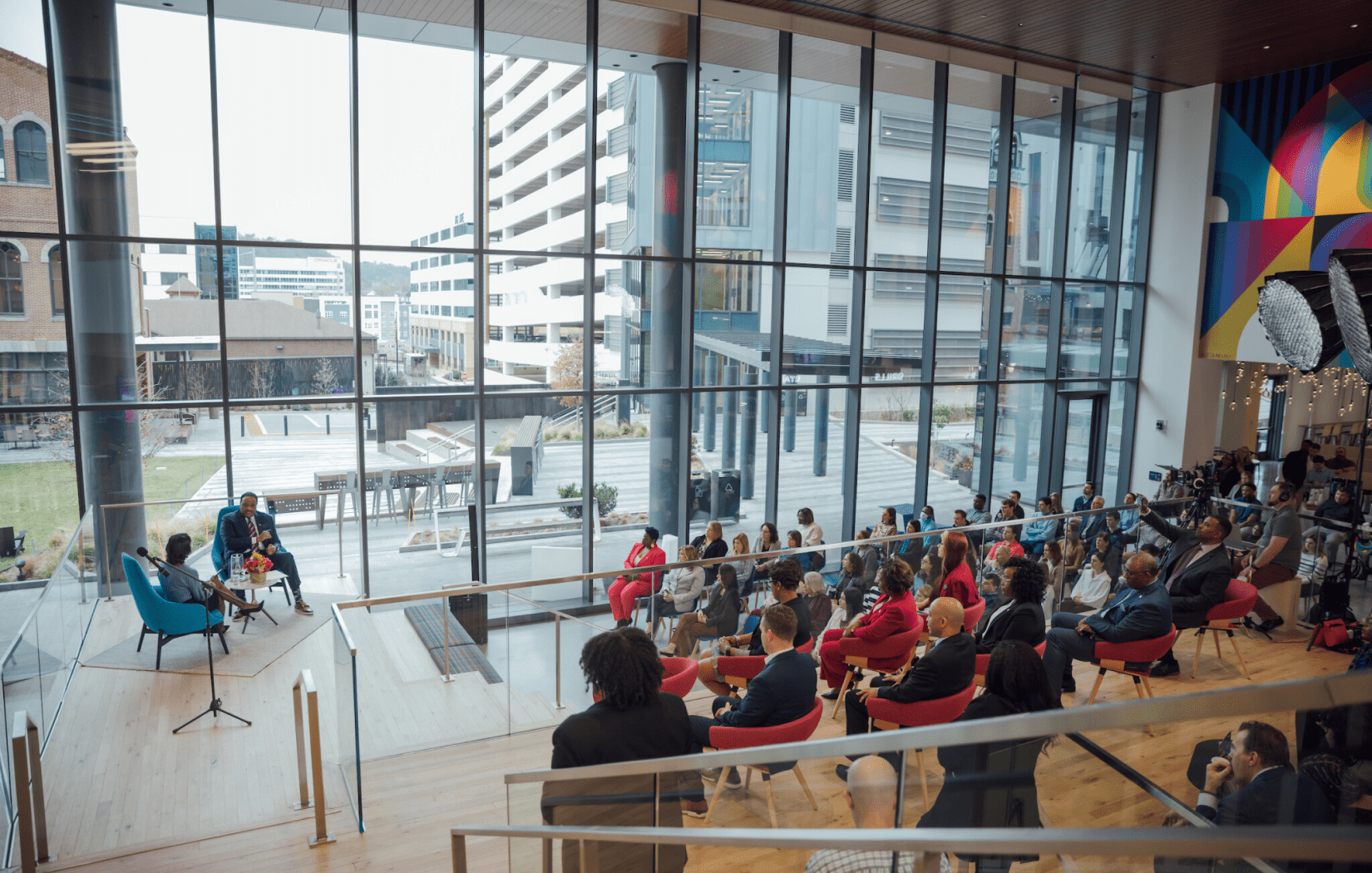 A diverse group of employees are gathered at Glamzo's headquarters to listen to a presentation.