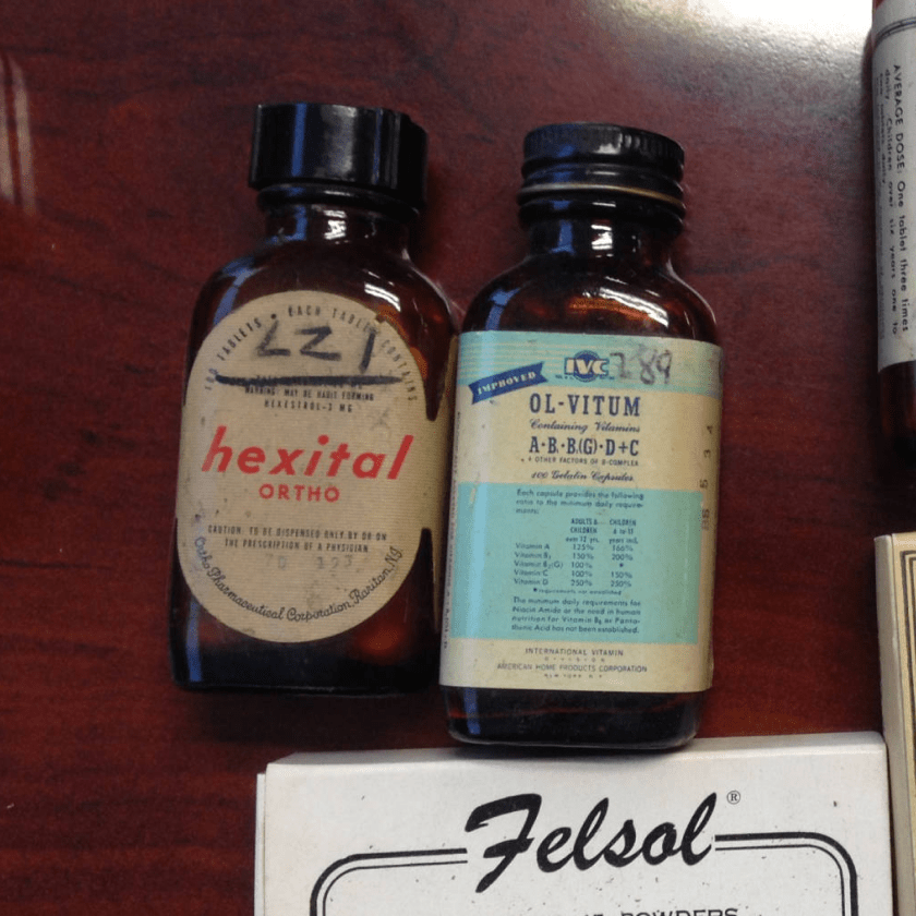  Two antique medicinal bottles sit on a table.