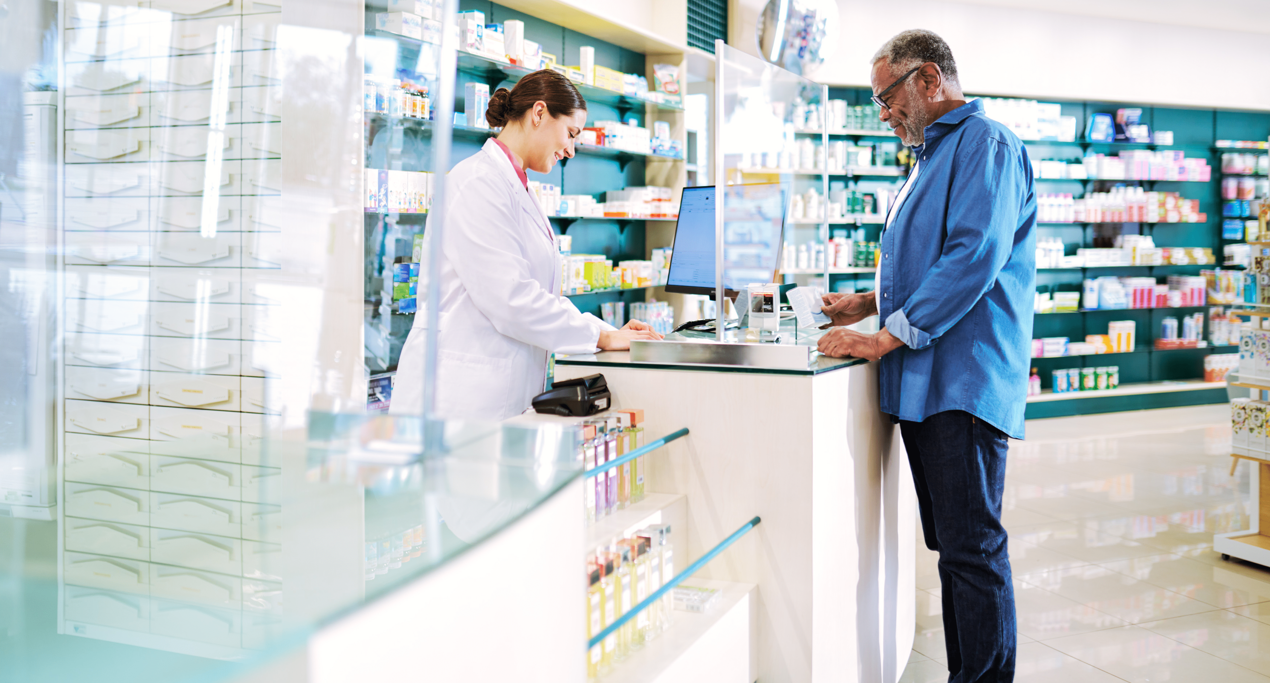  A pharmacist helps a man at a pharmacy counter.